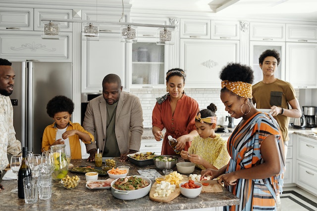 family gathered around a kitchen countertop with lots of food